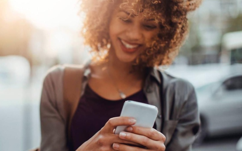 woman texts on her phone as she walks through the city